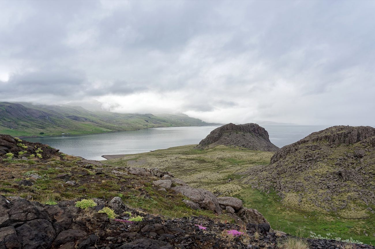 Eskifjörður séð af fjallinu: sjórinn, byggðin og klettabeltið.